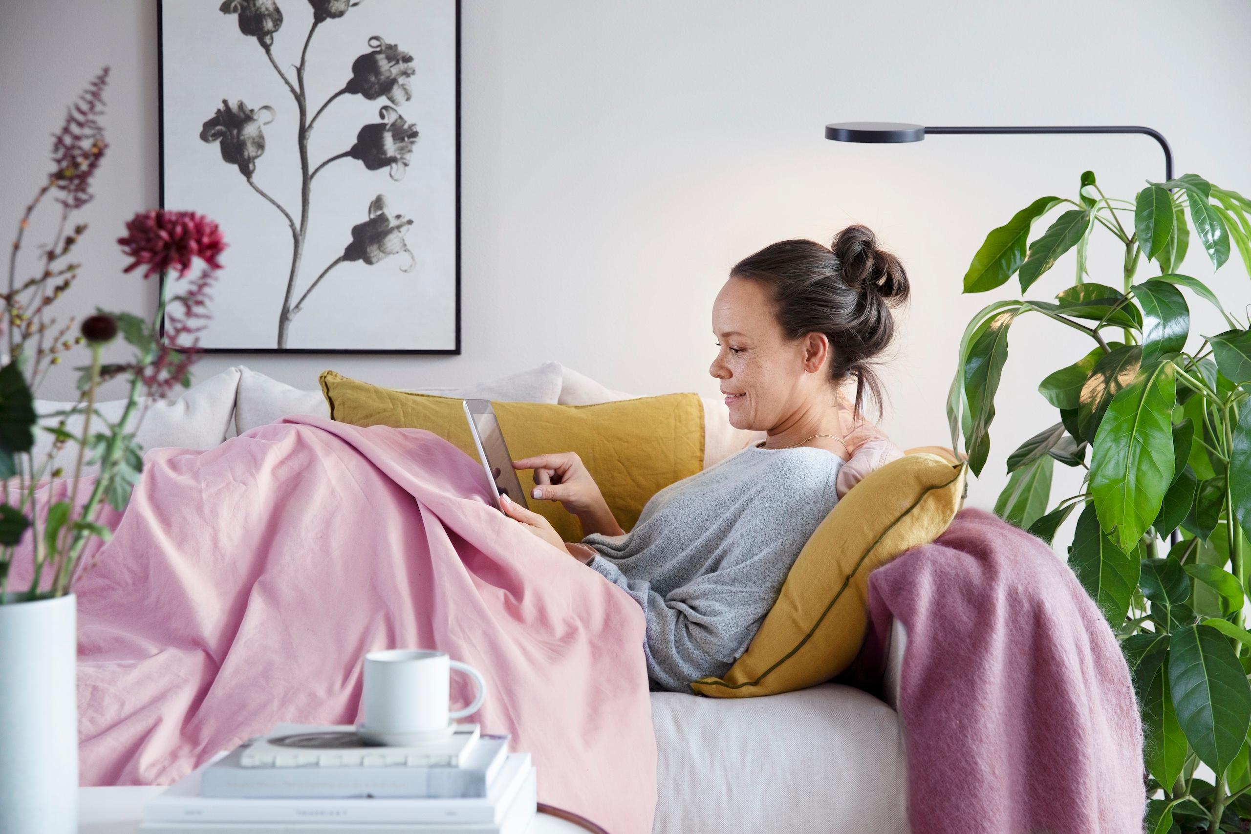 Kvinna som ligger i soffa med en Ipad.