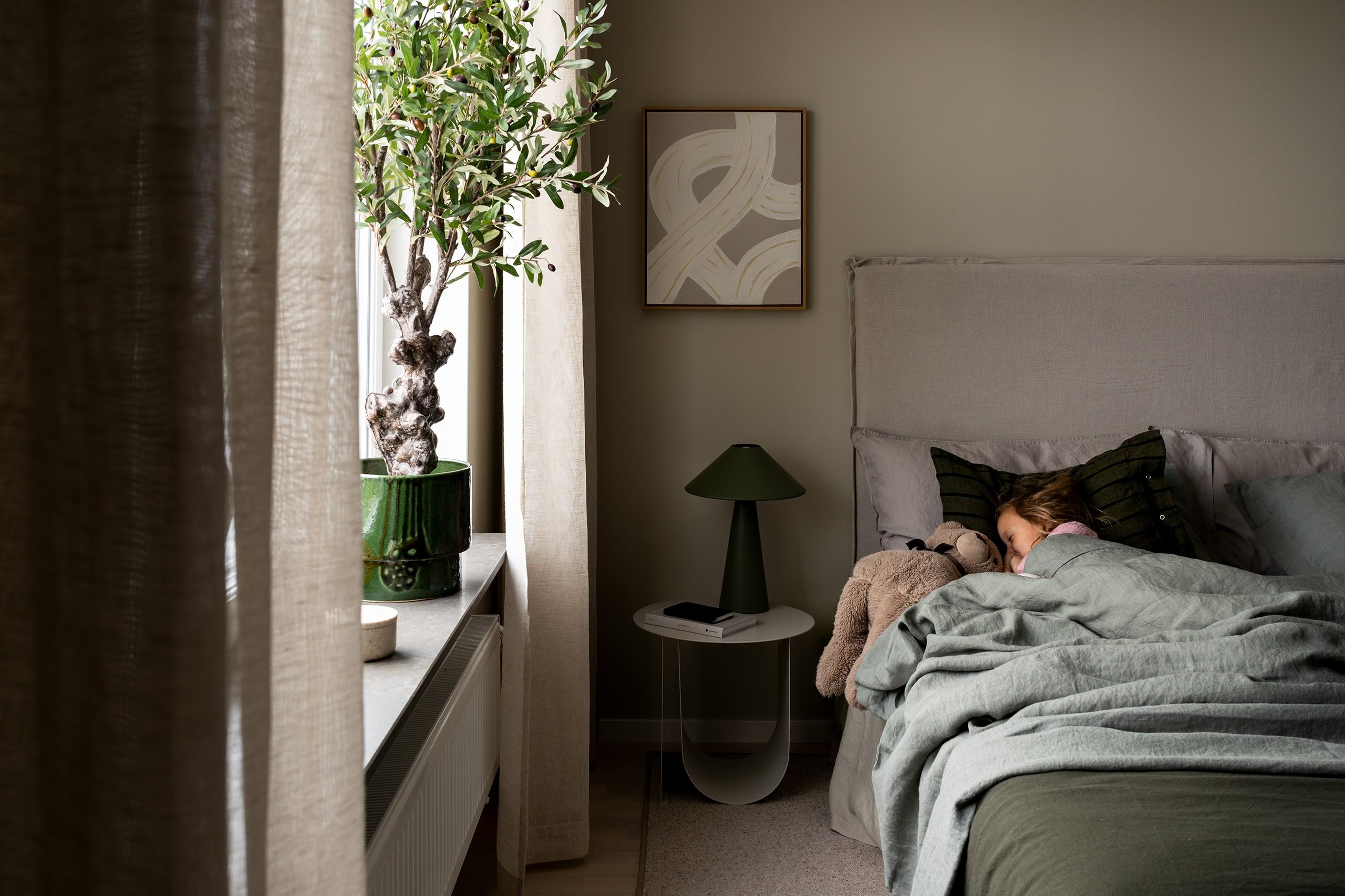 Barn sover i en dubbelsäng med sitt gosedjur i ett sovrum.